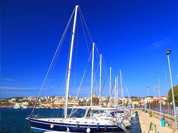 Sunny pier with sail boats at anchor in Lavrion harbor, Attica, Greece