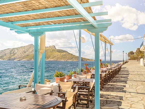 Summer photo with panoramic view from Aegina island in Greece. Beautiful place for making lunch on seafront with wooden roof of bar and restaurant.