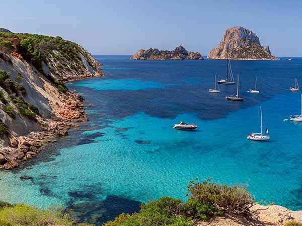 Hyper panorama of Cala Hort with sea sailing yachts and the mountain Es Vedra. Ibiza, Balearic Islands, Spain