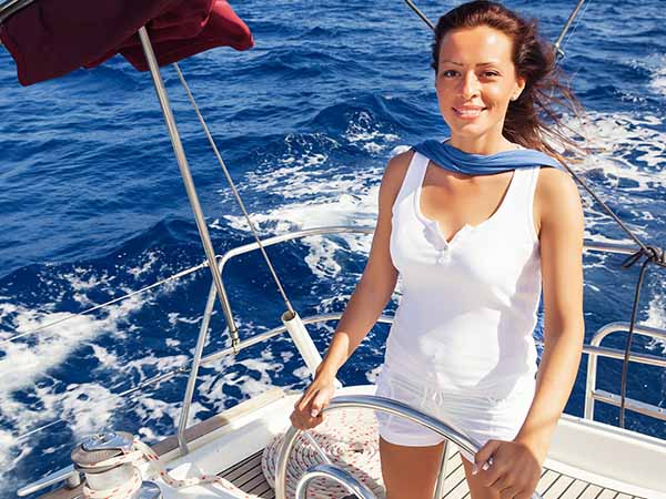 Female skipper navigating a sailboat.
