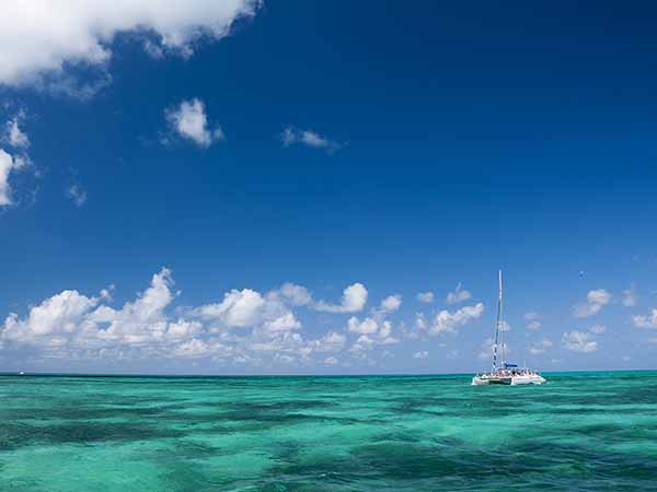 White catamaran with tourists on turquoise ocean near Cayo Blanco, Cuba