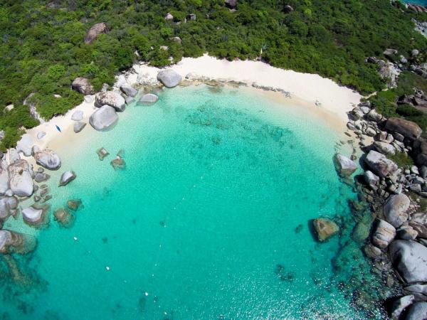 Arial photo of Devil's Bay. A horseshoe shaped bay with turquoise water and sandy beach with large rocks to the side.
