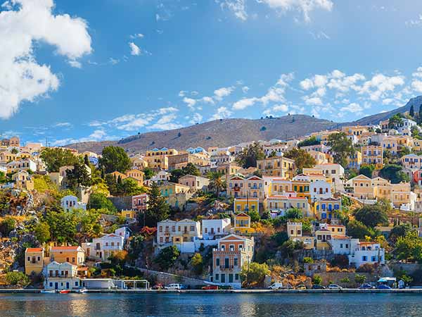 Panoramic shot of the Harbour at Symi Greece with a traditional fishing boat in the foreground. Greece Europe.
