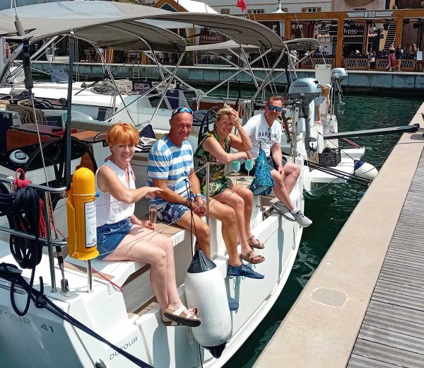 Crew sitting aboard a yacht, moored in a harbour on the Sardinia flotilla
