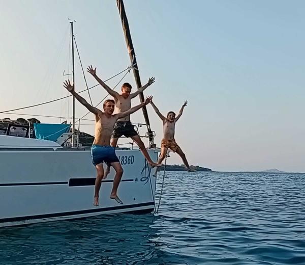 People jumping off the side of a yacht having fun on the Sardinia Flotilla