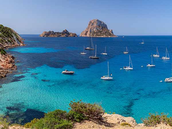 Hyper panorama of Cala Hort with sea sailing yachts and the mountain Es Vedra. Ibiza, Balearic Islands, Spain